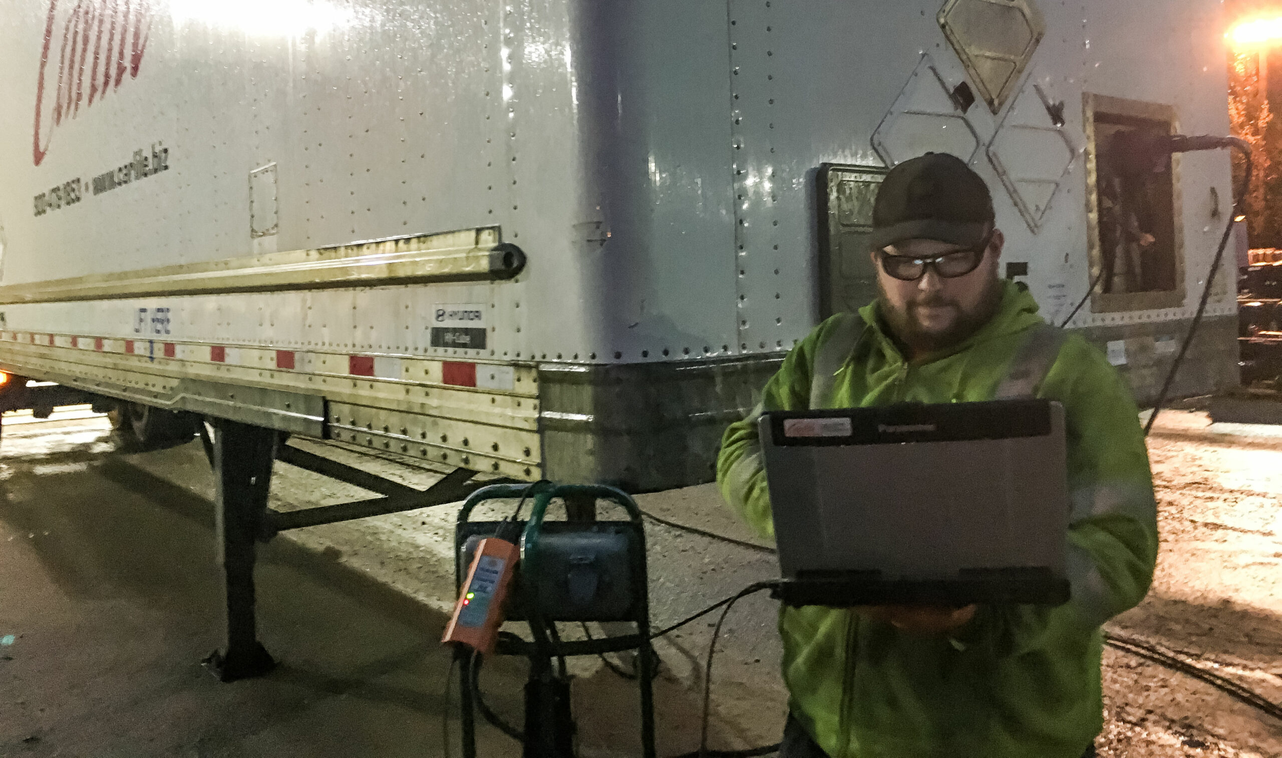 Carlile Transportation technician holding a diagnostic laptop beside a trailer