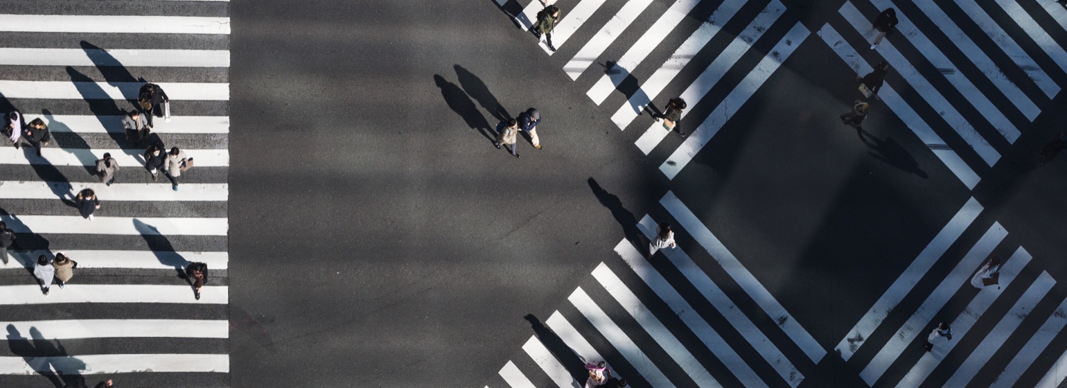 An overhead view of people crossing a geometric city intersection