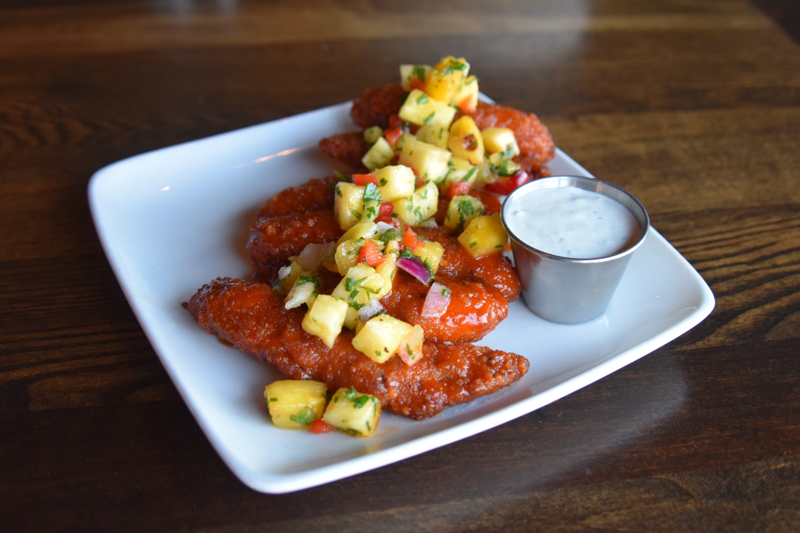 Crisp chicken tenders with colorful pineapple salsa and a cup of dipping sauce