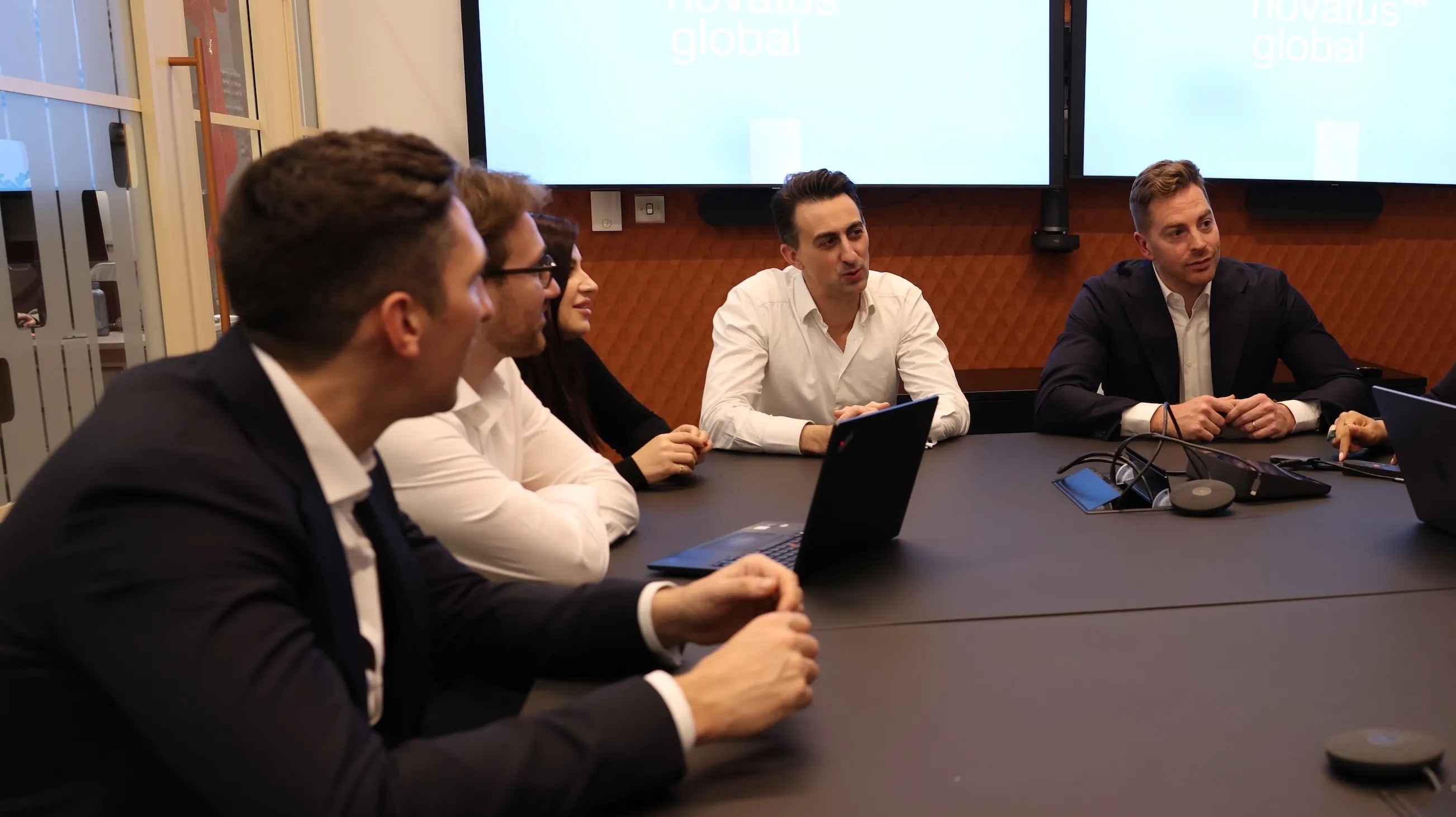 Novatus colleagues discussing work around a meeting table