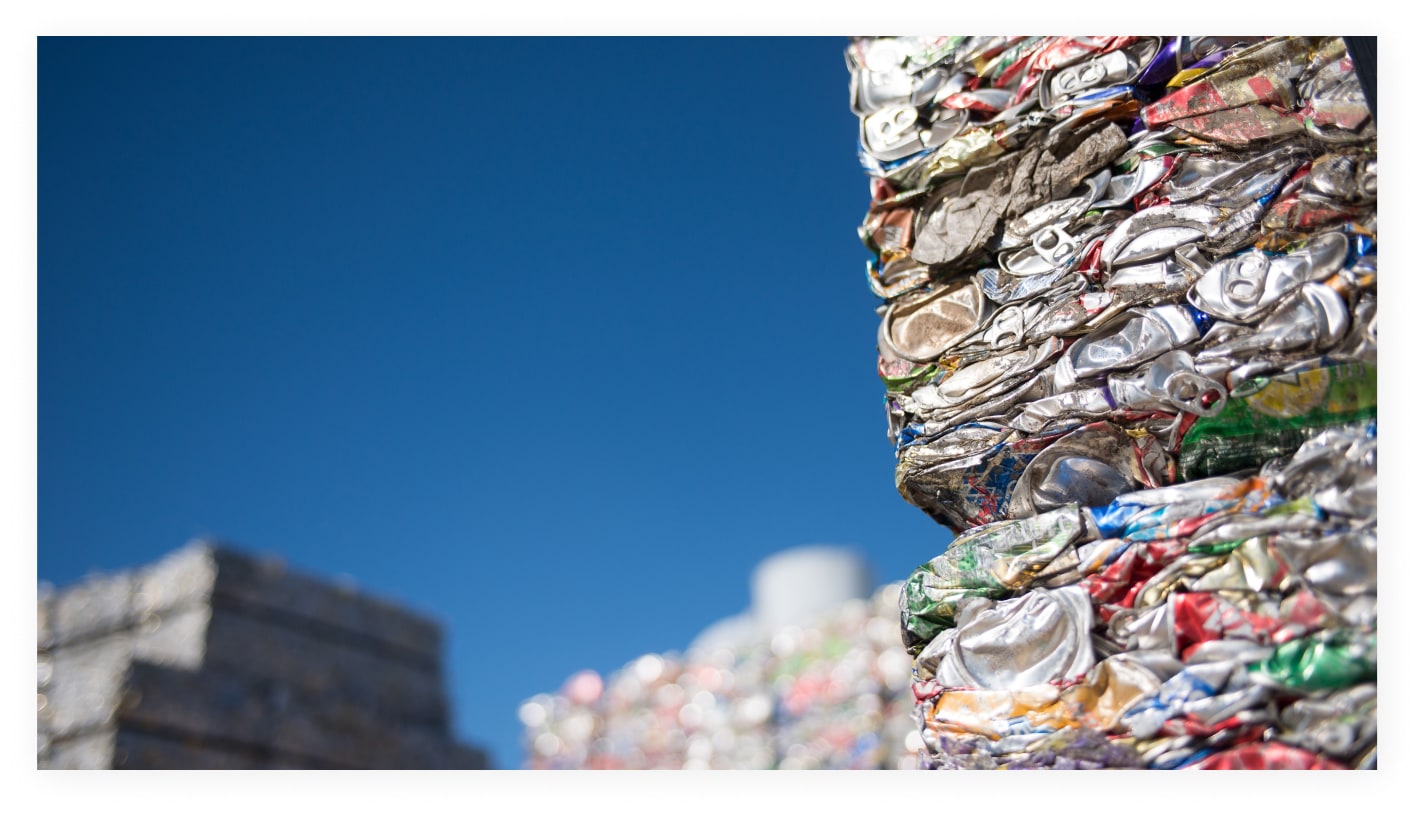 Compressed bales of used aluminum beverage cans stacked outdoors
