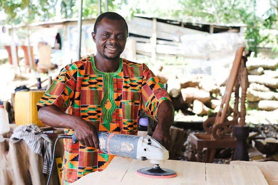 Ghanaian NOVICA artisan Eric Danquah smiling in his woodworking studio