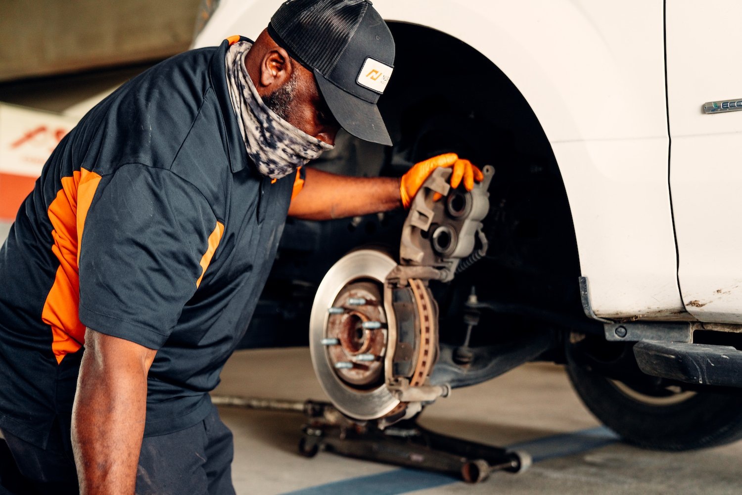 A NuBrakes technician holding a brake caliper beside an exposed wheel hub