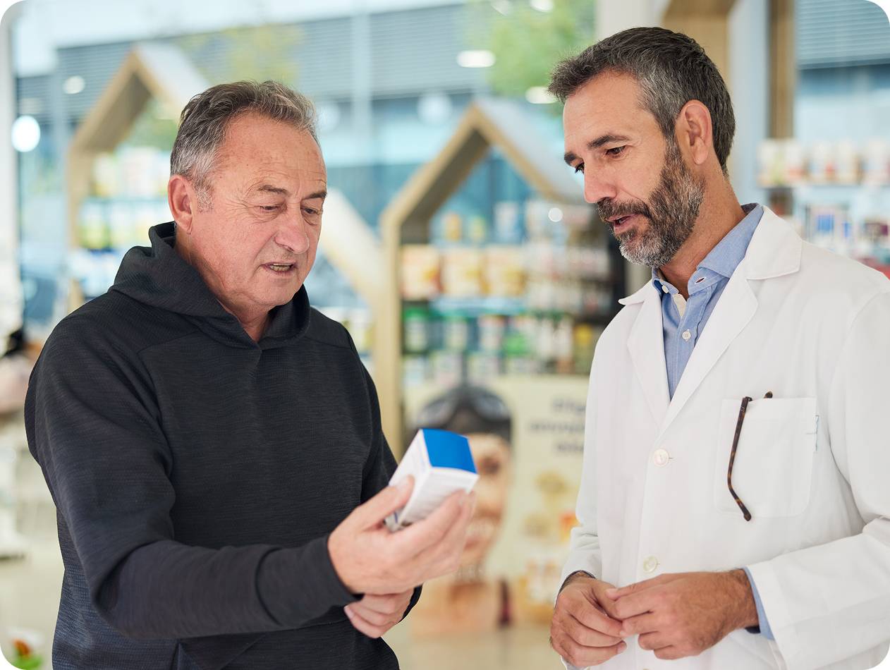 A pharmacist and a colleague reviewing pharmacy information on a laptop