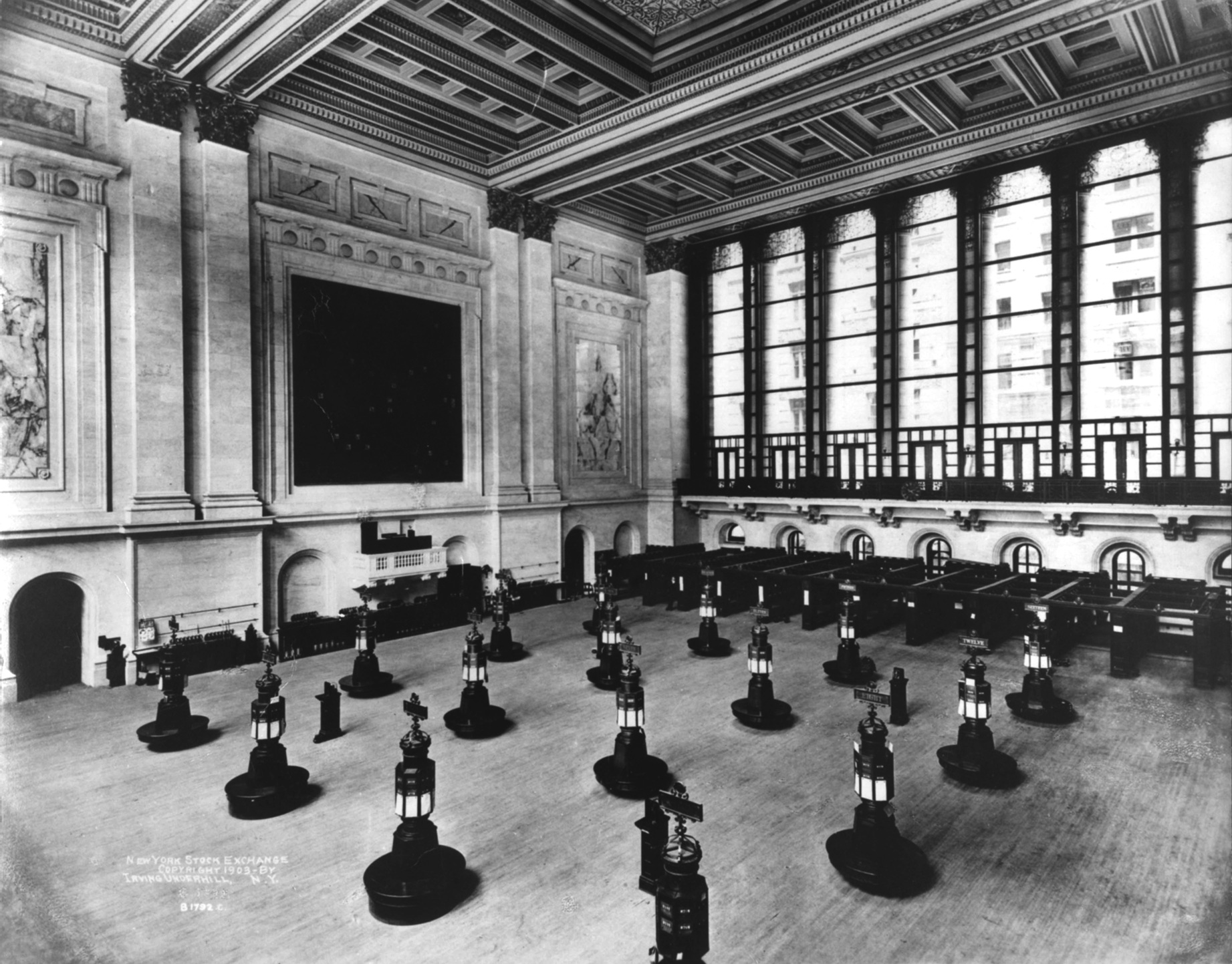 The NYSE trading floor in 1903, with trading posts beneath a high ornamental ceiling