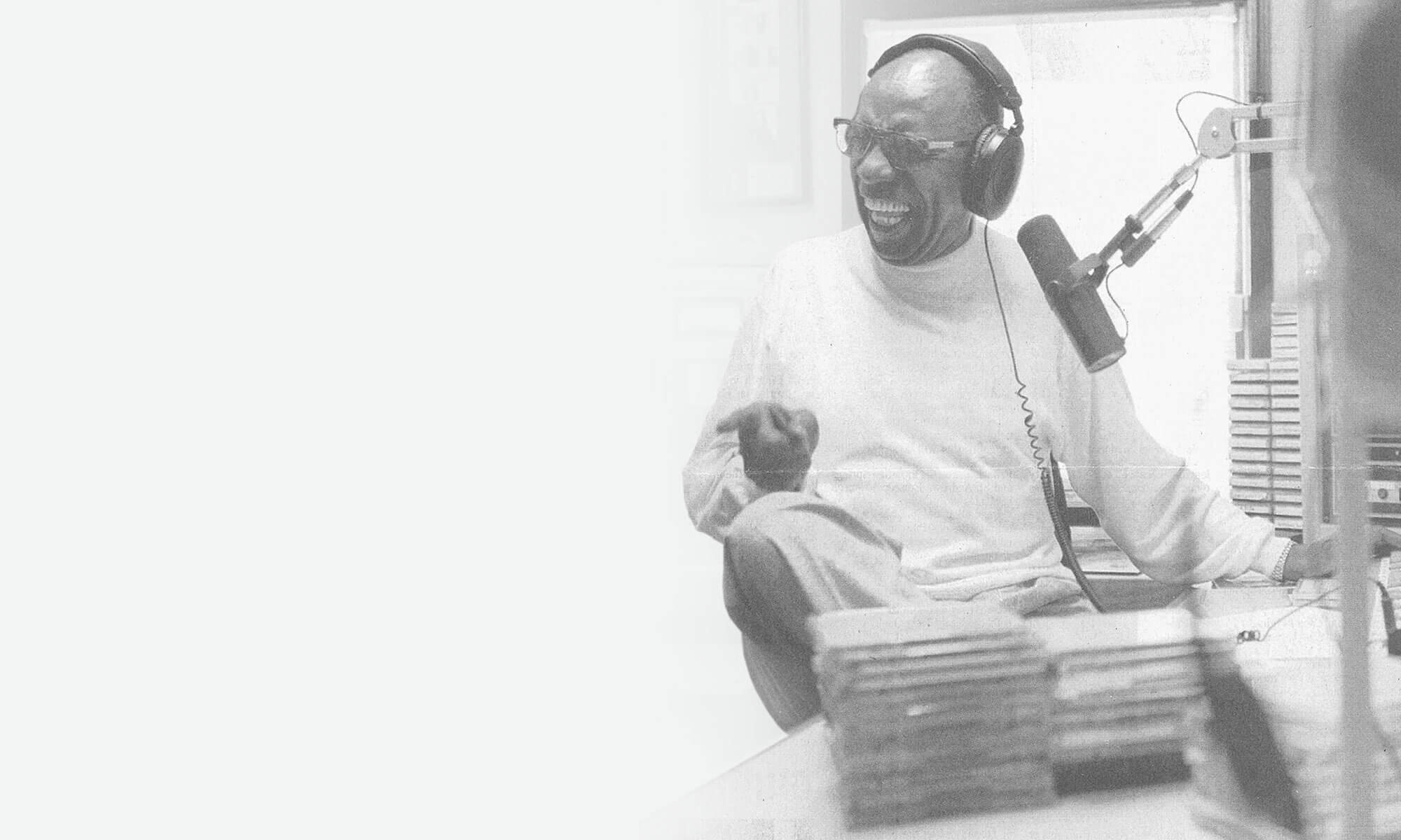 Shelley Stewart smiling behind a radio microphone in a black-and-white archival photograph