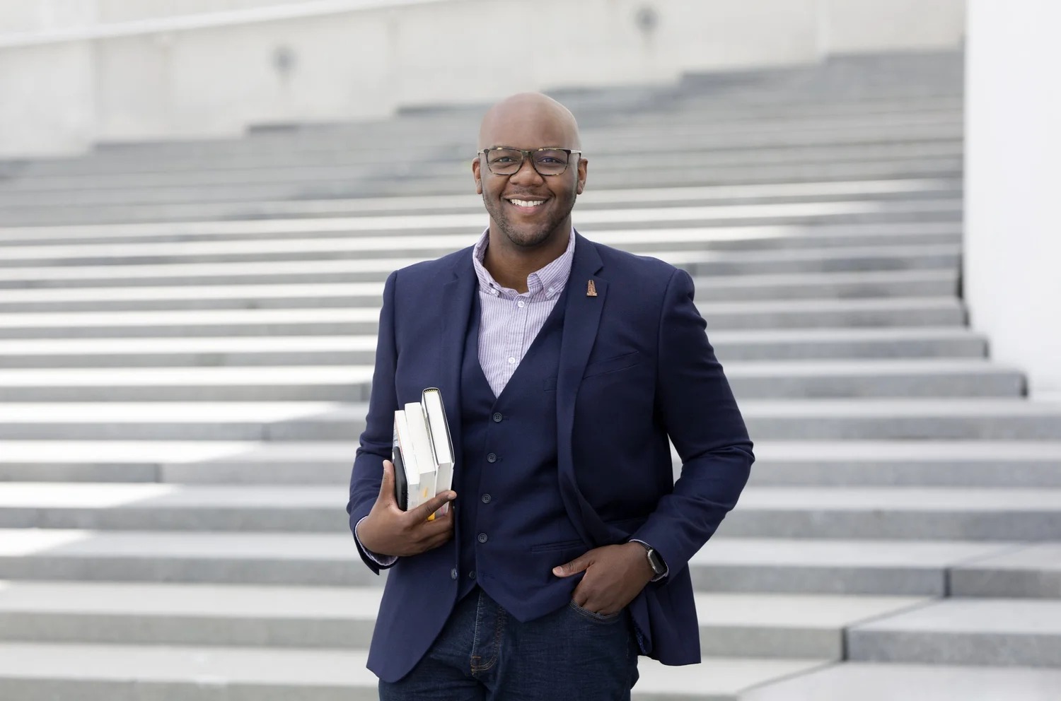Oak Lane founder Reginauld Williams standing on outdoor steps, holding books