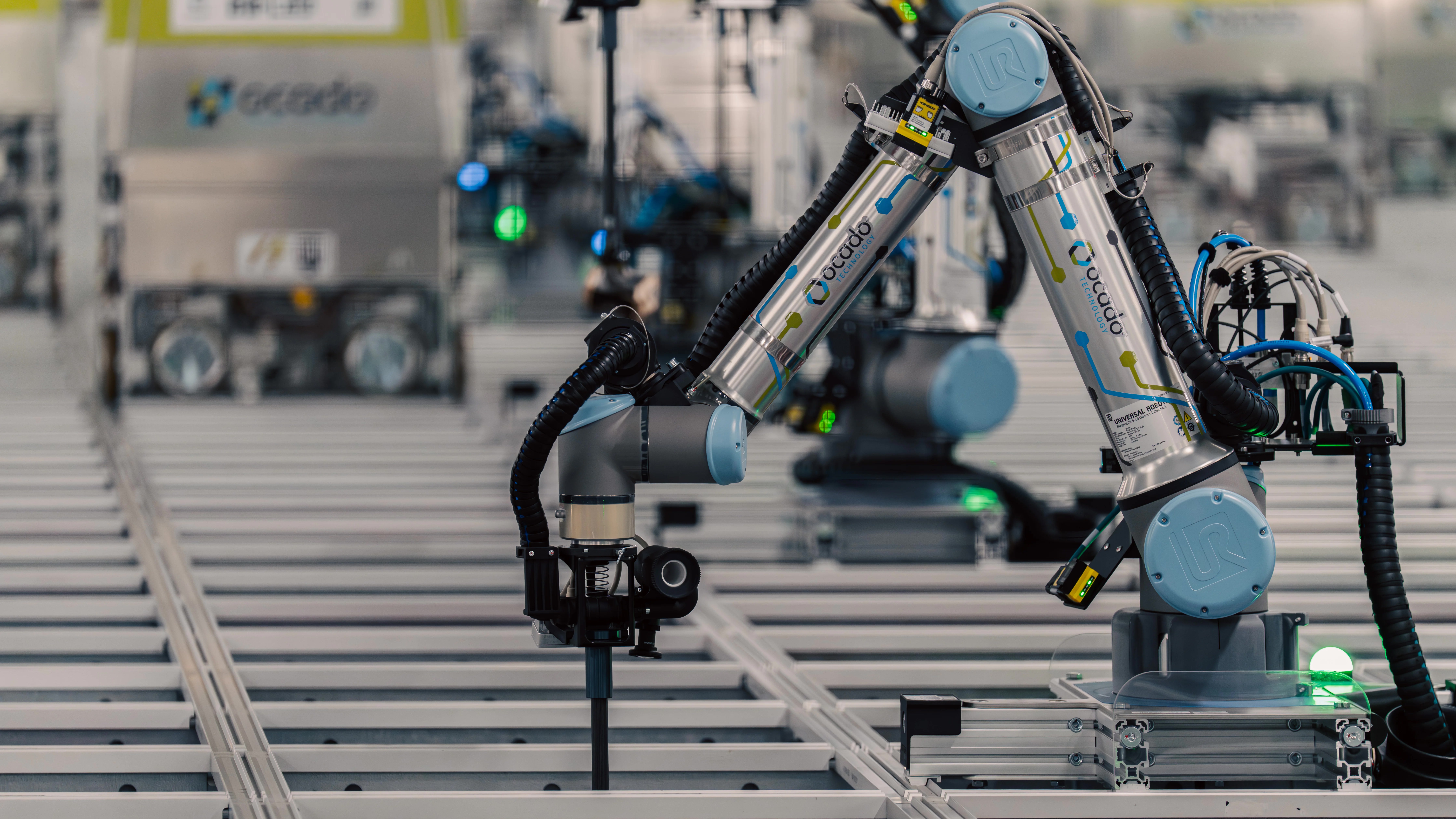 Ocado robots and an on-grid robotic picking arm operating above a grocery storage grid
