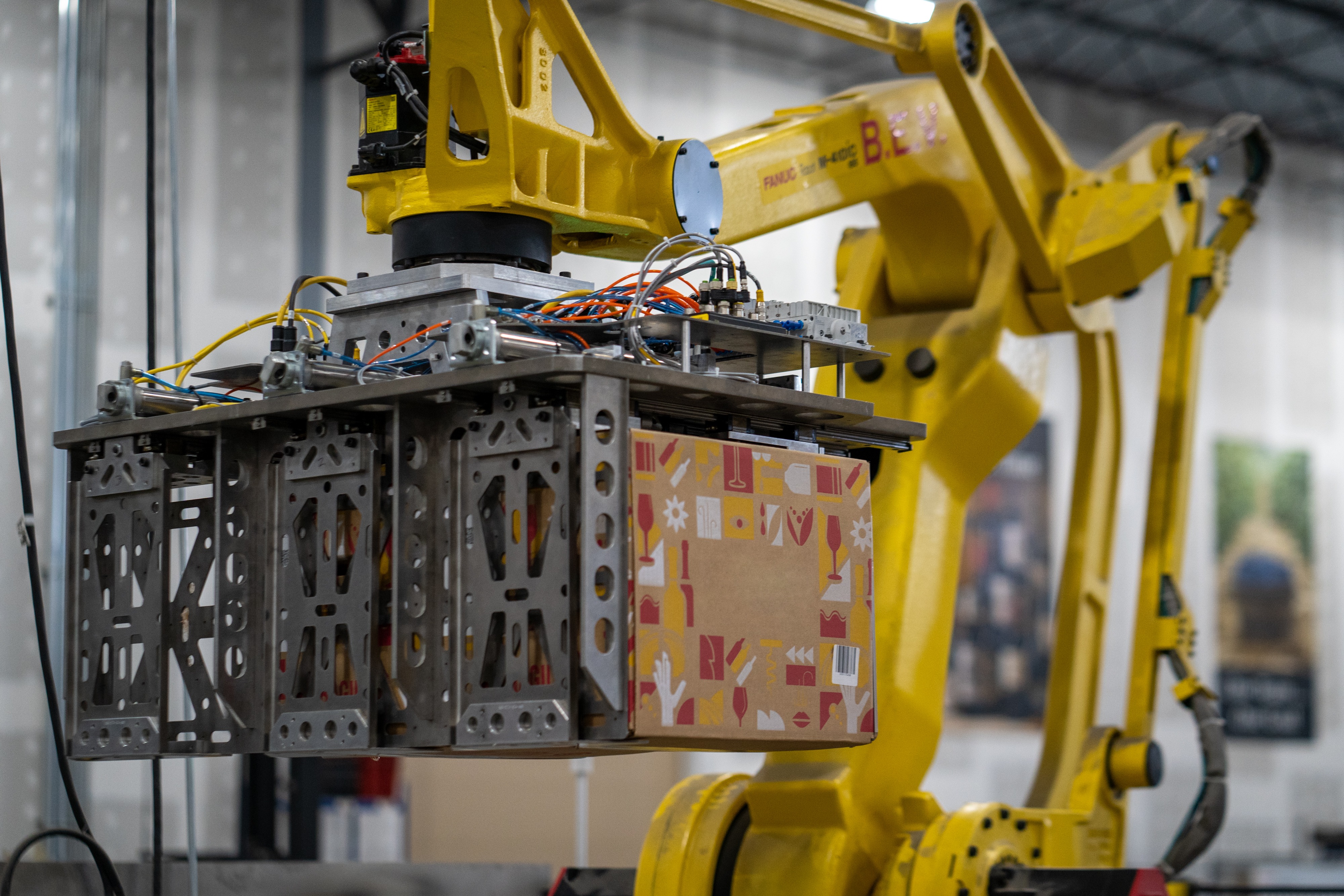Yellow robotic palletizer handling a packaged case in an ODW warehouse image
