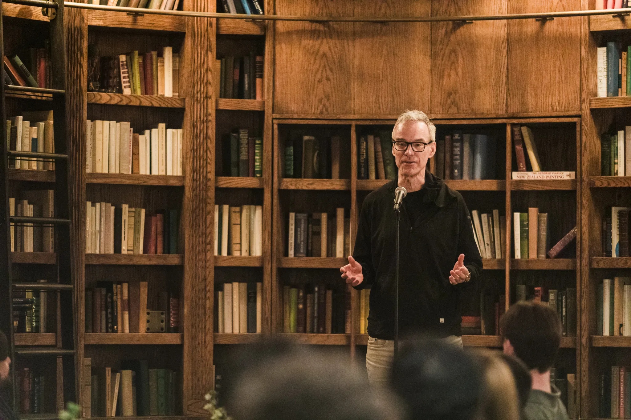 Oege de Moor speaking into a microphone in a book-lined room at Sequoia’s Arc story slam