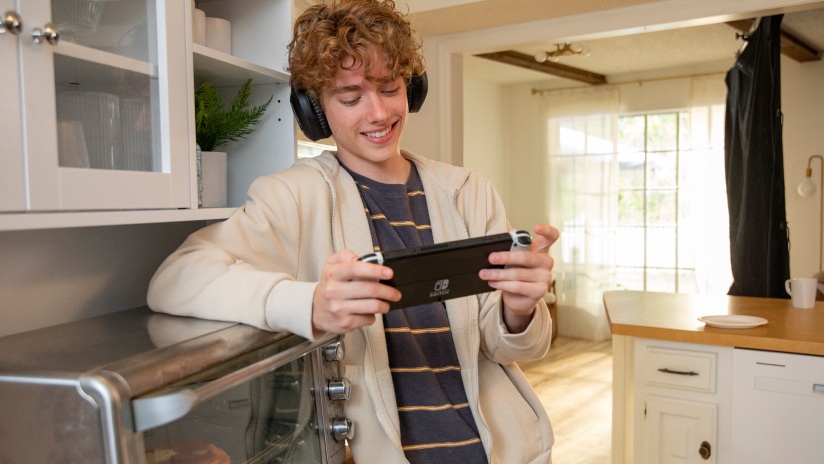 OG&E SmartHours promotional photograph of a teenager playing a handheld game in a kitchen