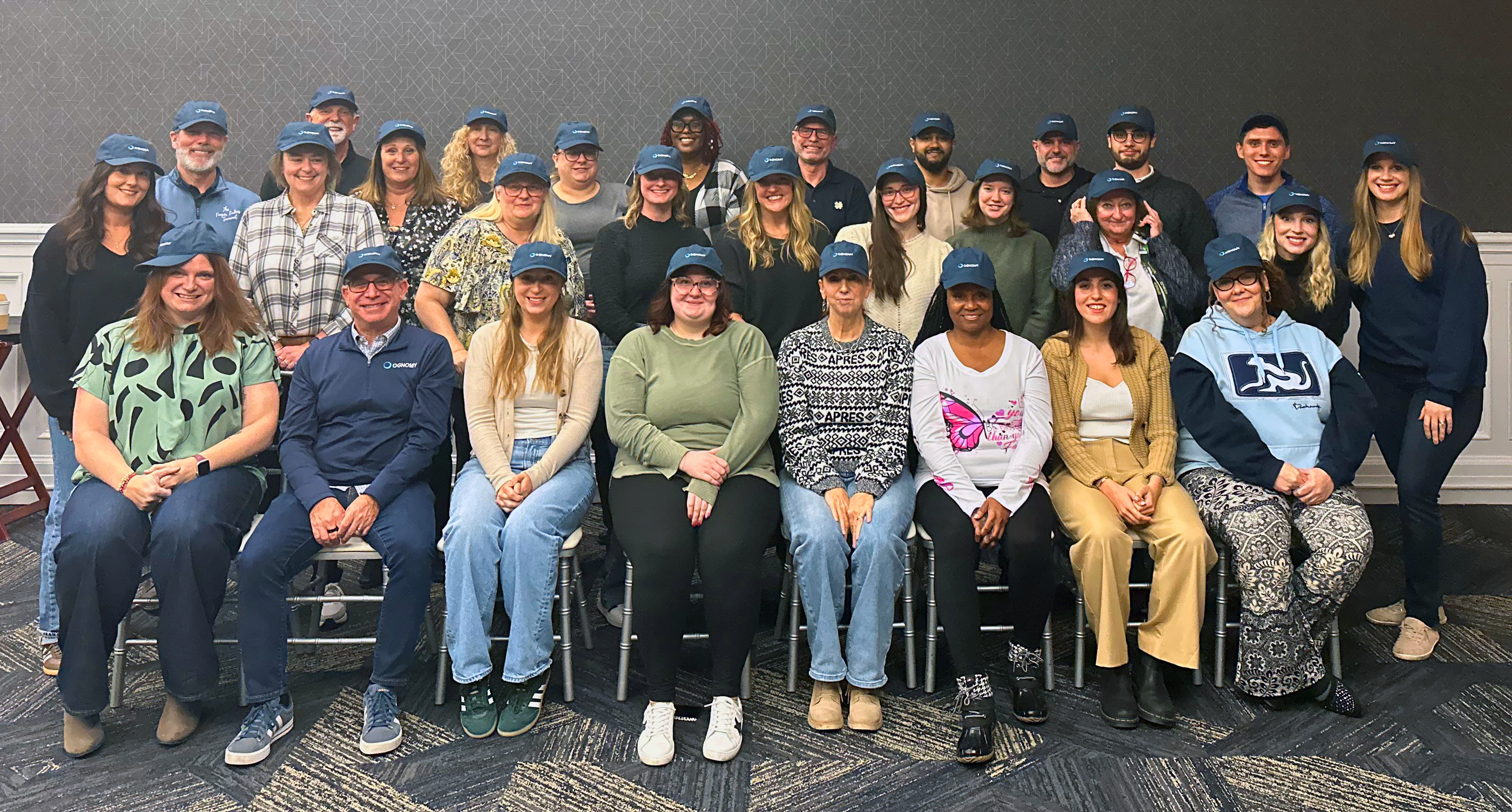 Ognomy team members posing together in matching navy caps