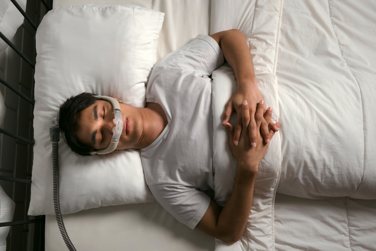 An illustrative photograph of a person in bed wearing a CPAP mask