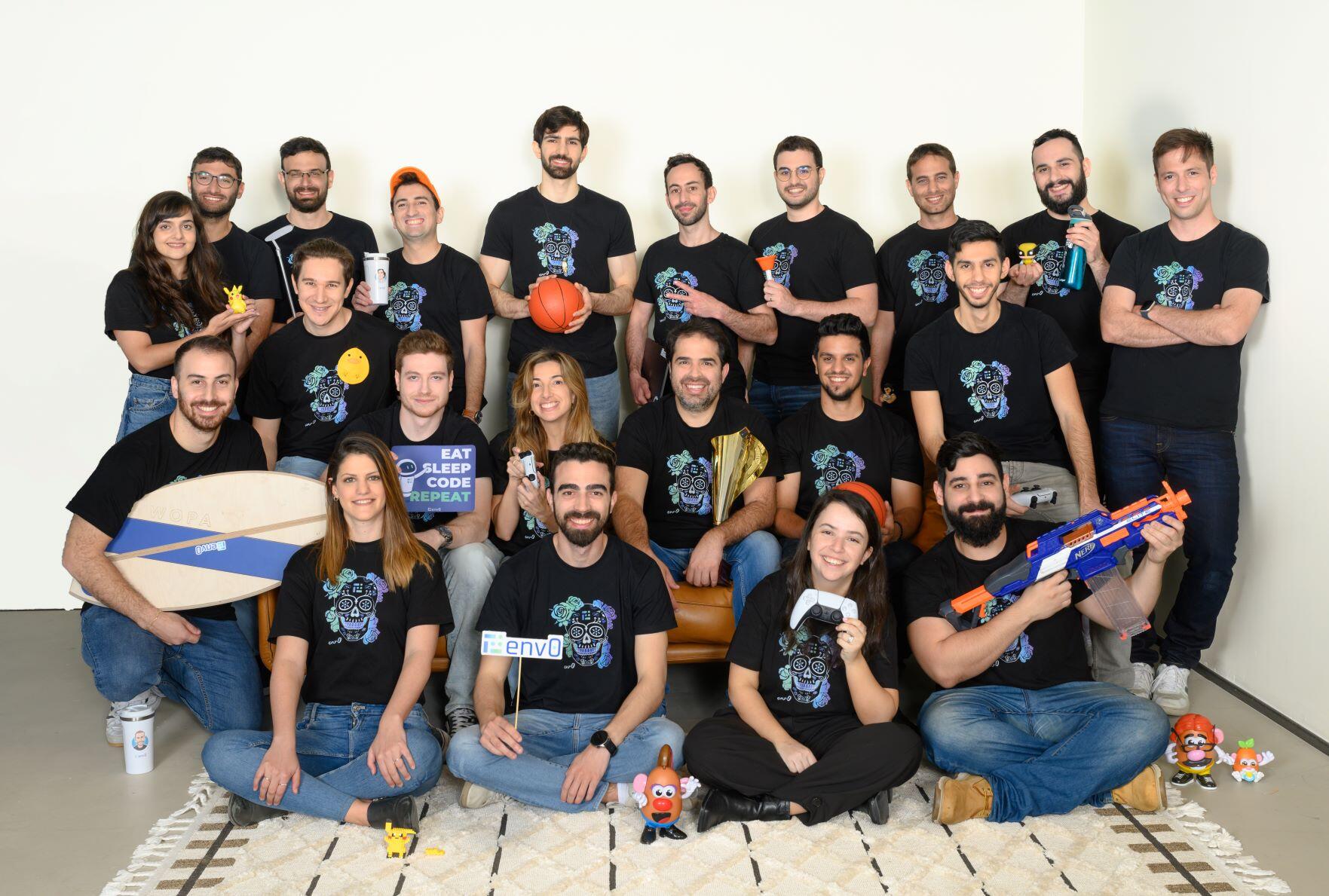 env0 team posing with matching shirts, a surfboard, basketball and game controllers