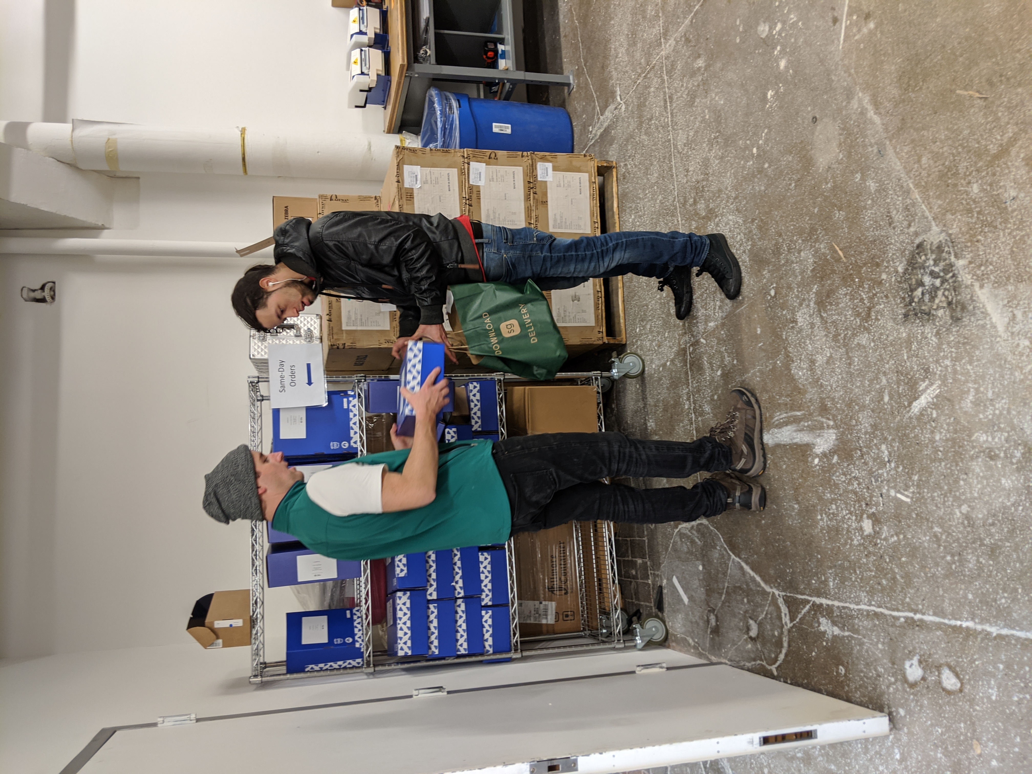 A worker hands a boxed order to a courier inside Ohi’s Manhattan micro-warehouse