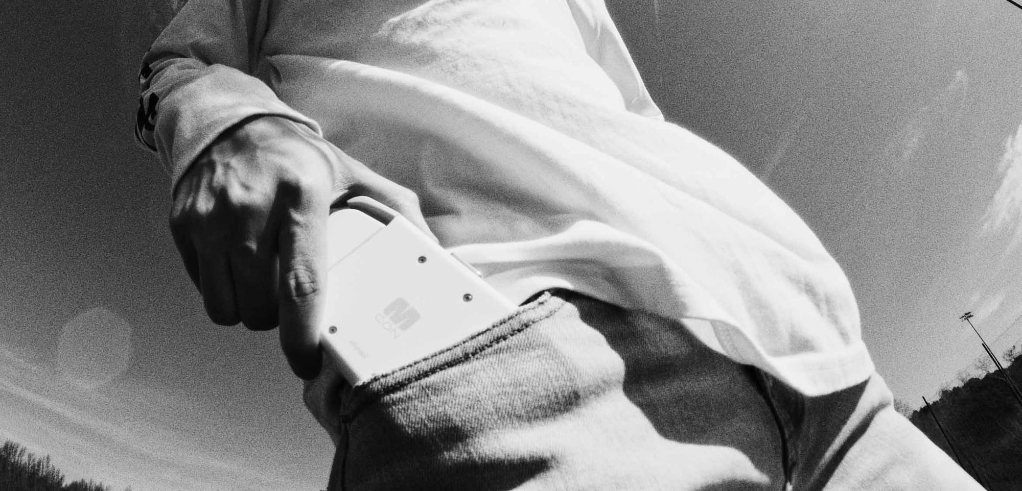 A person slides the compact white Ohsnap MCON mobile controller into a jeans pocket