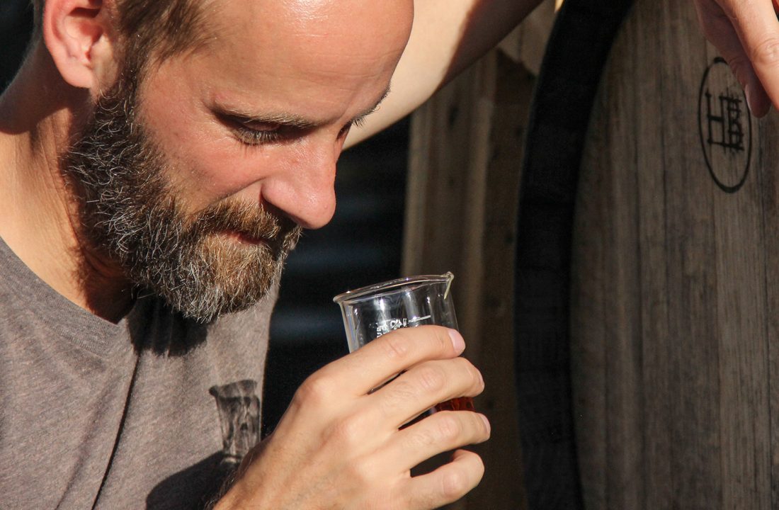 Carl Bender examining whiskey beside a barrel