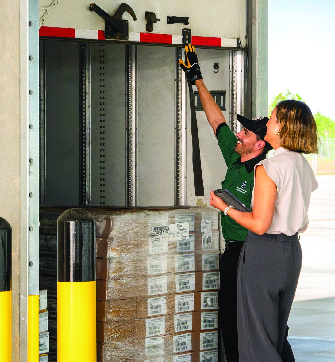 Two people discuss freight handling beside a pallet in an Old Dominion trailer