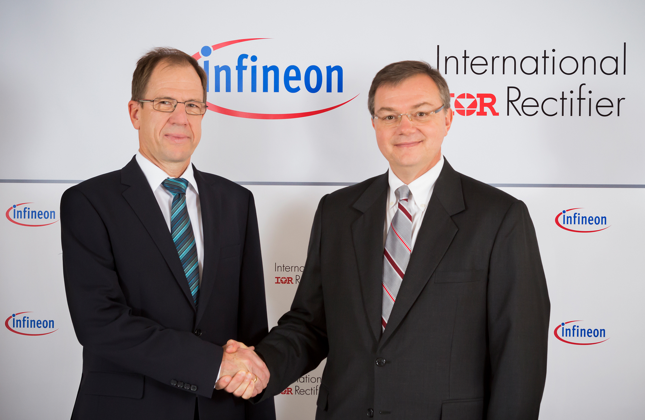 Reinhard Ploss, left, and Oleg Khaykin, right, shake hands at the 2014 International Rectifier acquisition announcement.