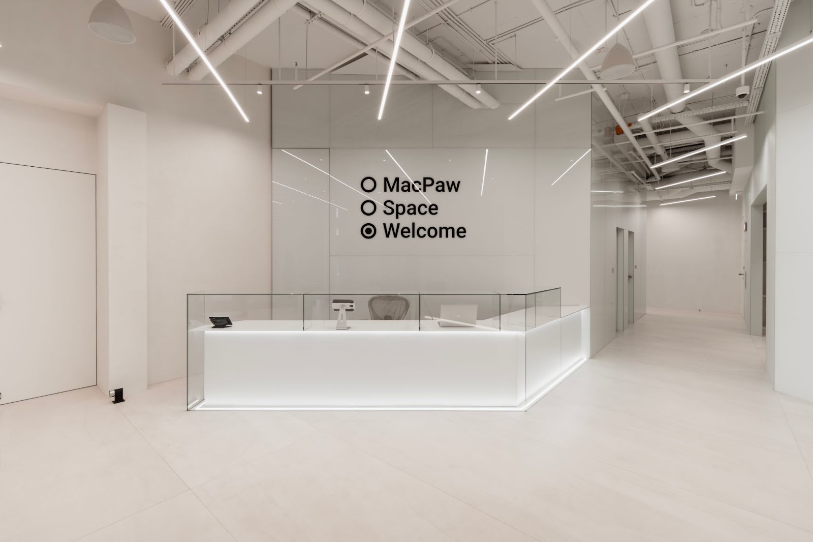 White reception desk and geometric lighting inside MacPaw Space in Kyiv