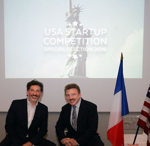 Olivier Attia, left, seated beside David Hamod at the 2016 USA Startup Competition, with French and American flags nearby.