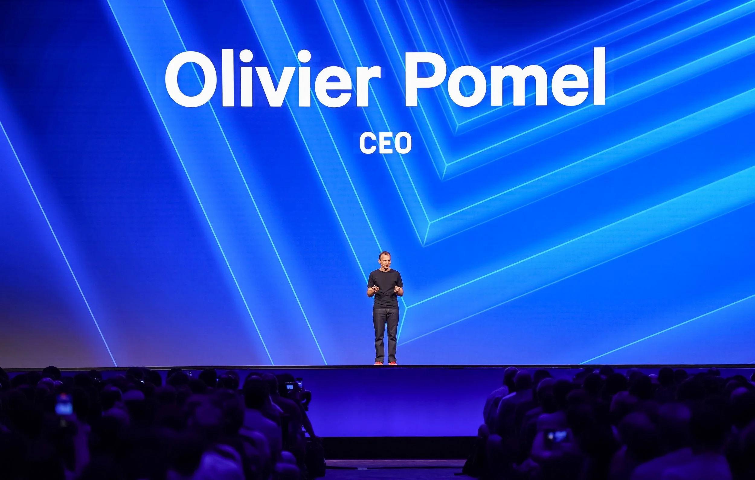 Olivier Pomel addressing the DASH audience in front of a blue geometric stage backdrop