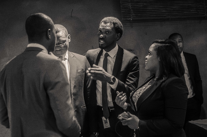 Olugbenga Agboola speaking with colleagues in an office