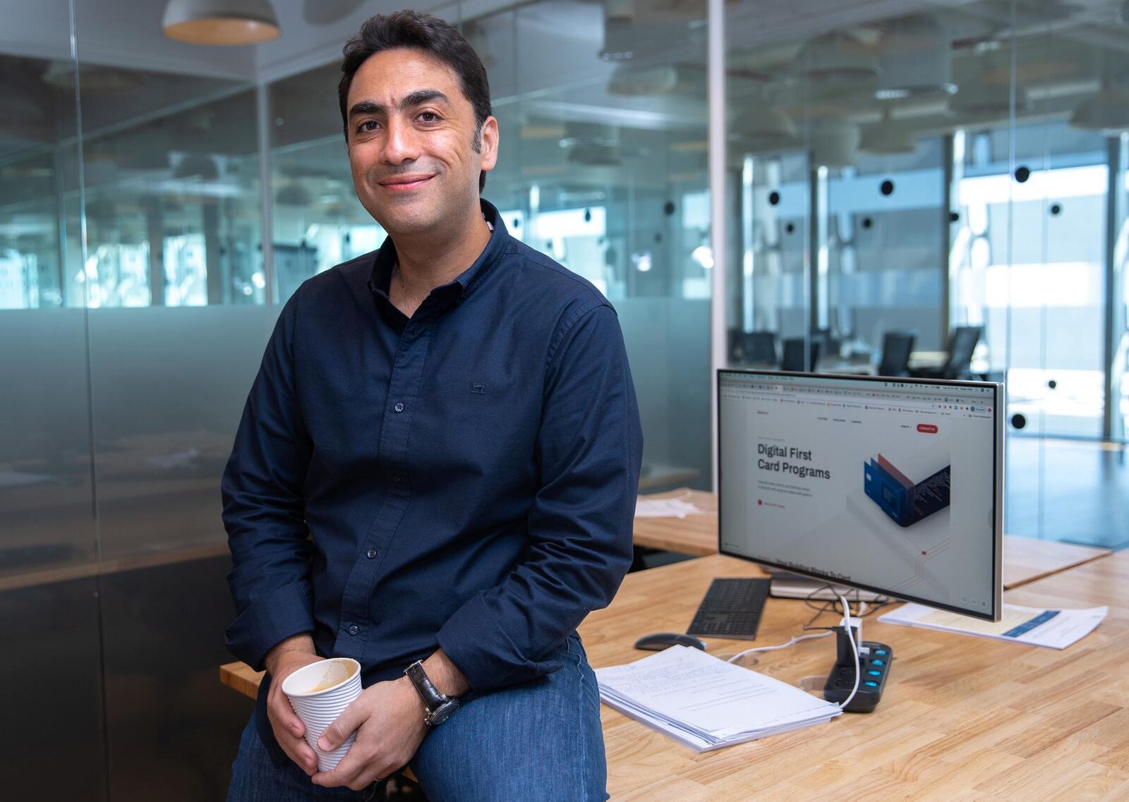 Omar Onsi beside a desk and a monitor displaying NymCard card programmes in Abu Dhabi
