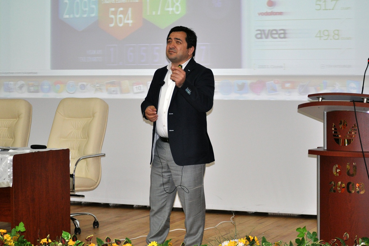 Omer Deveci speaking in front of a projected presentation at Gümüşhane University