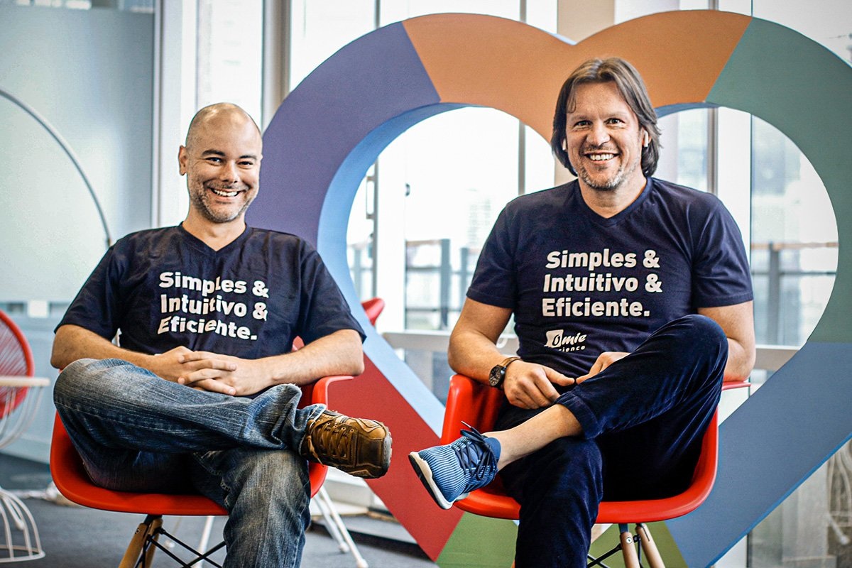 Omie founders Rafael Olmos, left, and Marcelo Lombardo, right, seated in red chairs