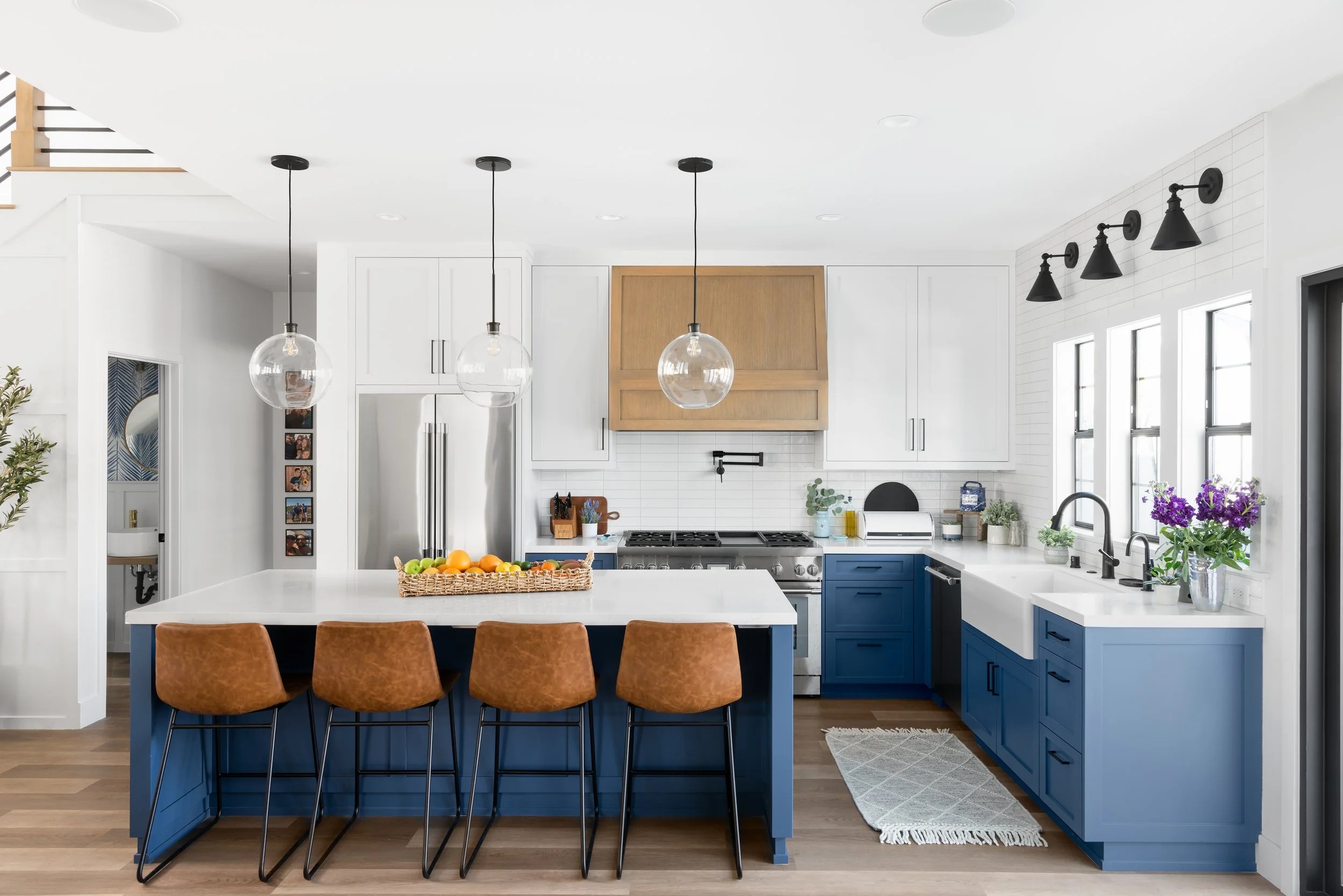 Completed Lakewood kitchen with blue cabinets, a white island and glass pendant lights