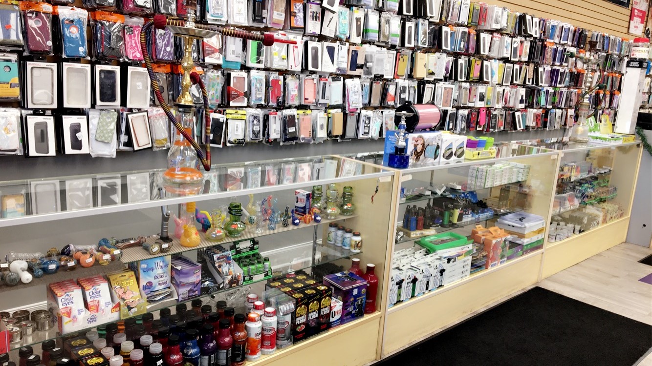 Inside One Wireless, with a long wall of packaged phone cases and glass counters filled with electronics and other merchandise