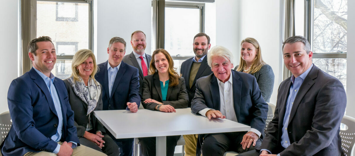 O'Neill and Associates team gathered around a table in a bright Boston office