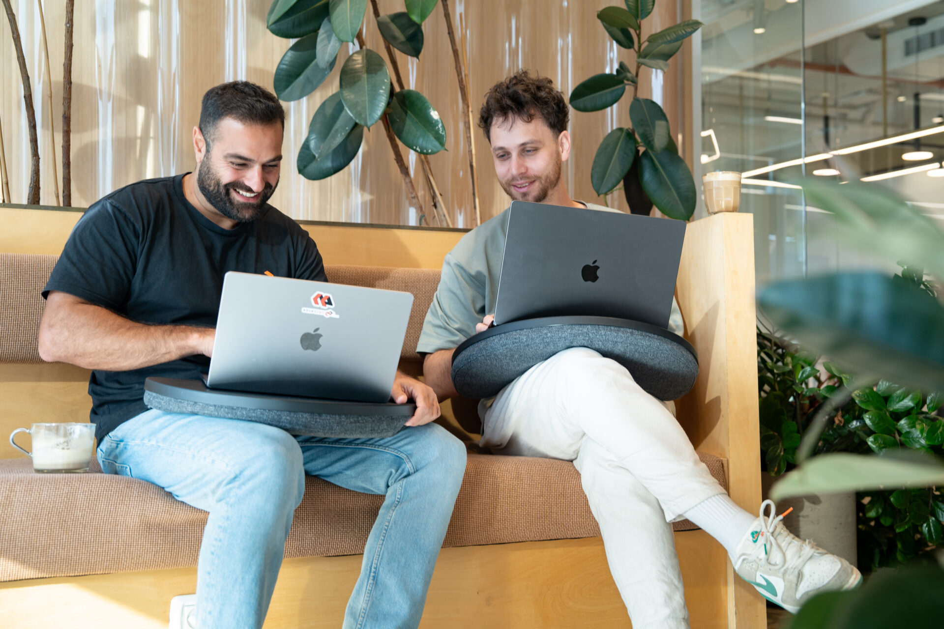 Two OneLayer team members working on laptops in an office seating area