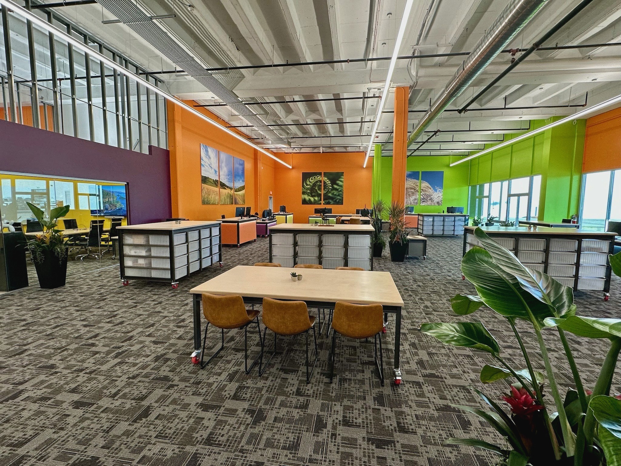 OnQ workplace interior with long tables, display installations and a high industrial ceiling