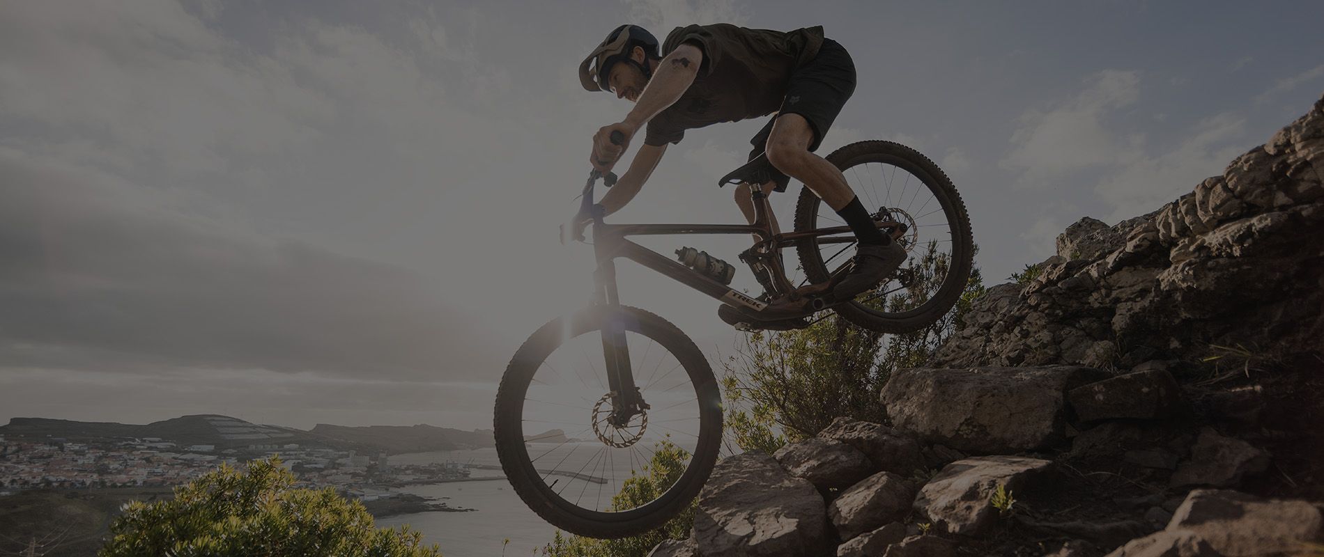 A mountain biker riding a Trek bicycle over rocky terrain
