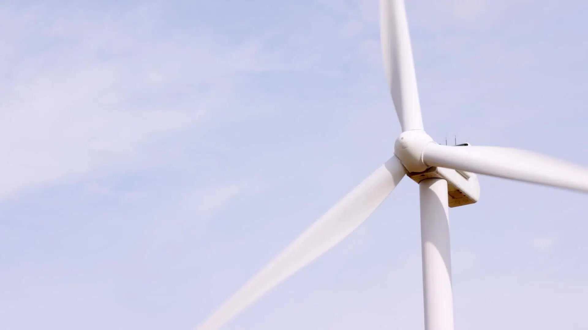 A wind turbine turns against a pale sky