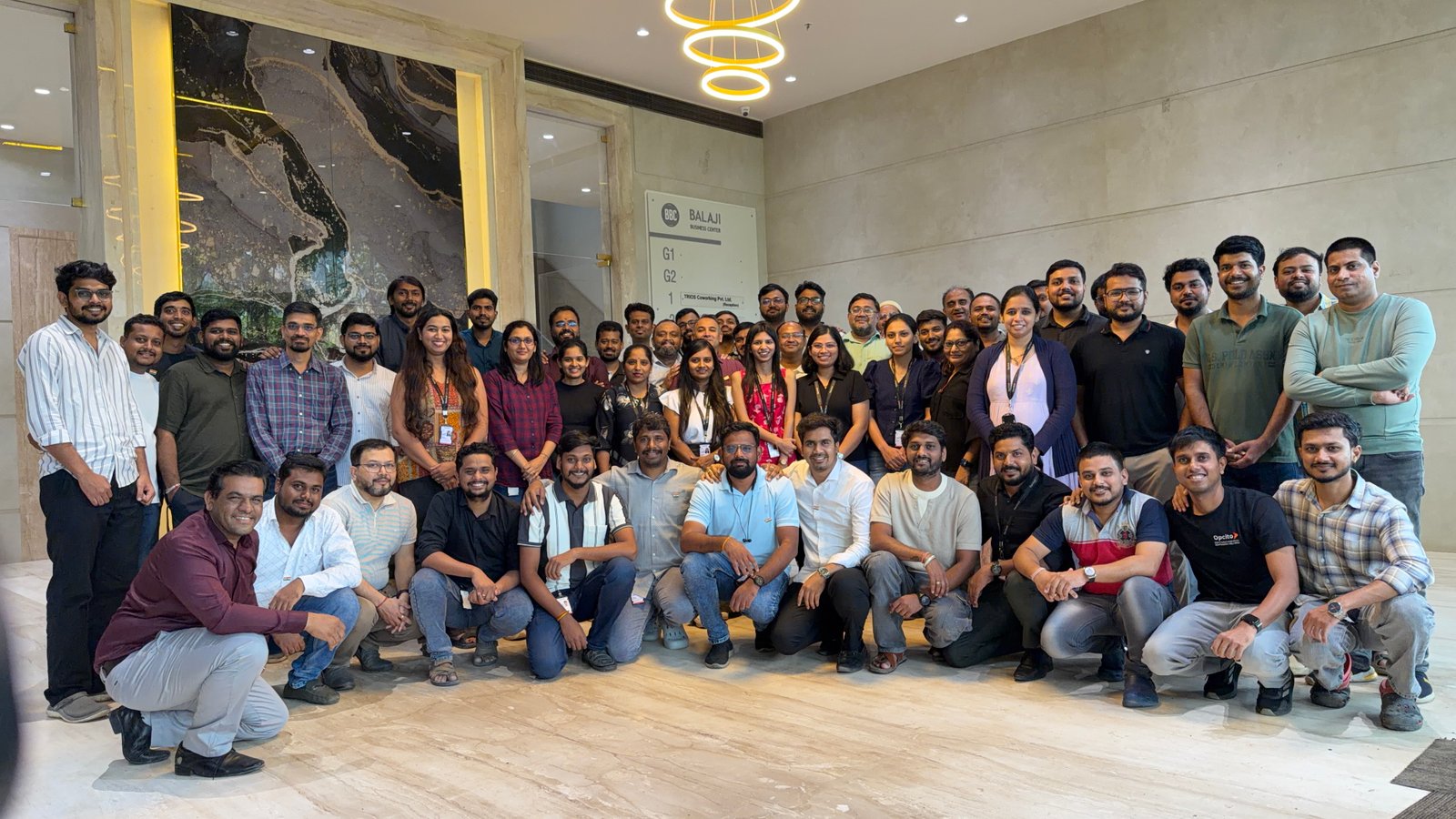 Opcito colleagues gathered for a group photograph inside a building lobby