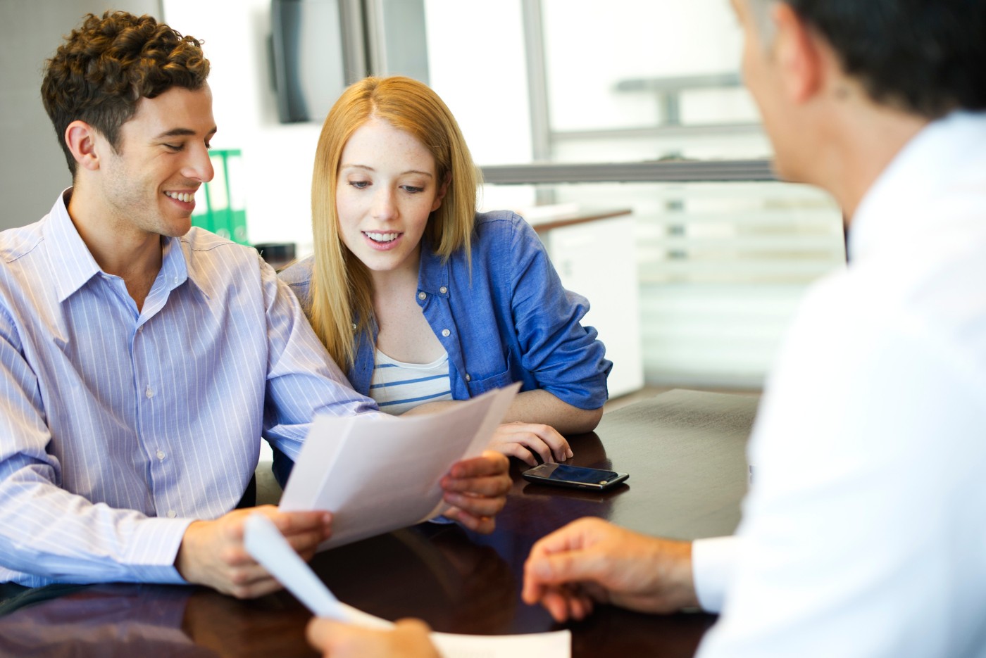 Two banking customers review paperwork with a consultant