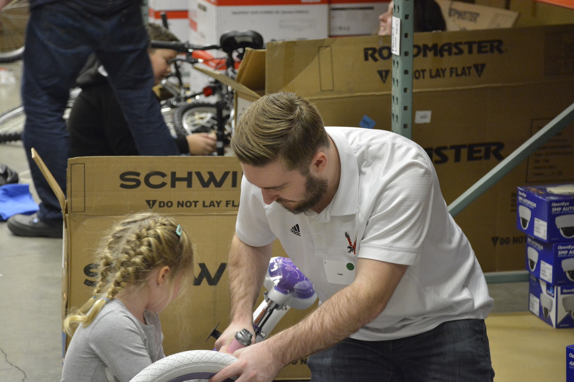 An adult and child working on a bicycle among bike boxes in OpenEye’s community photograph