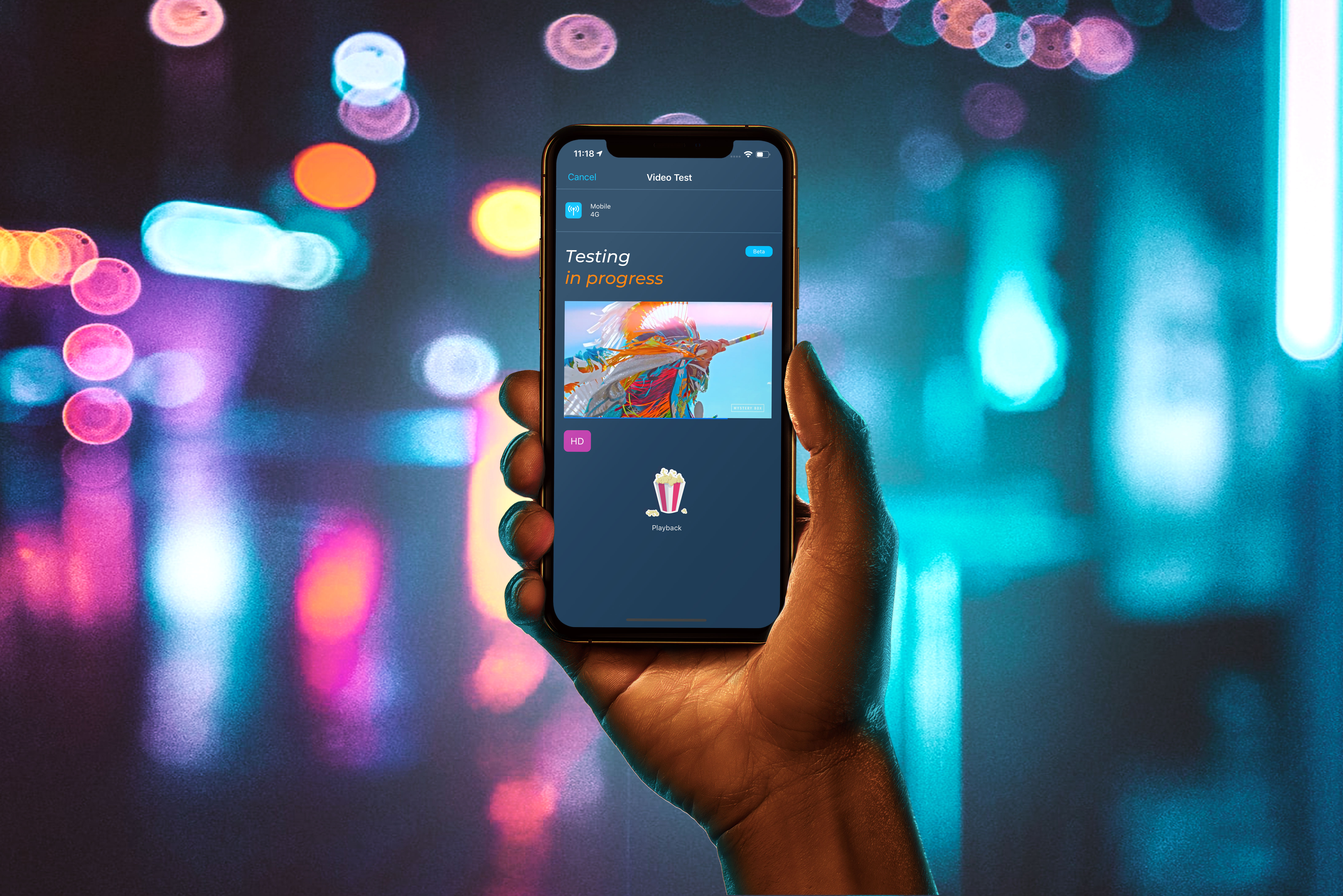 A hand holding an iPhone running the Opensignal video test against colorful city lights