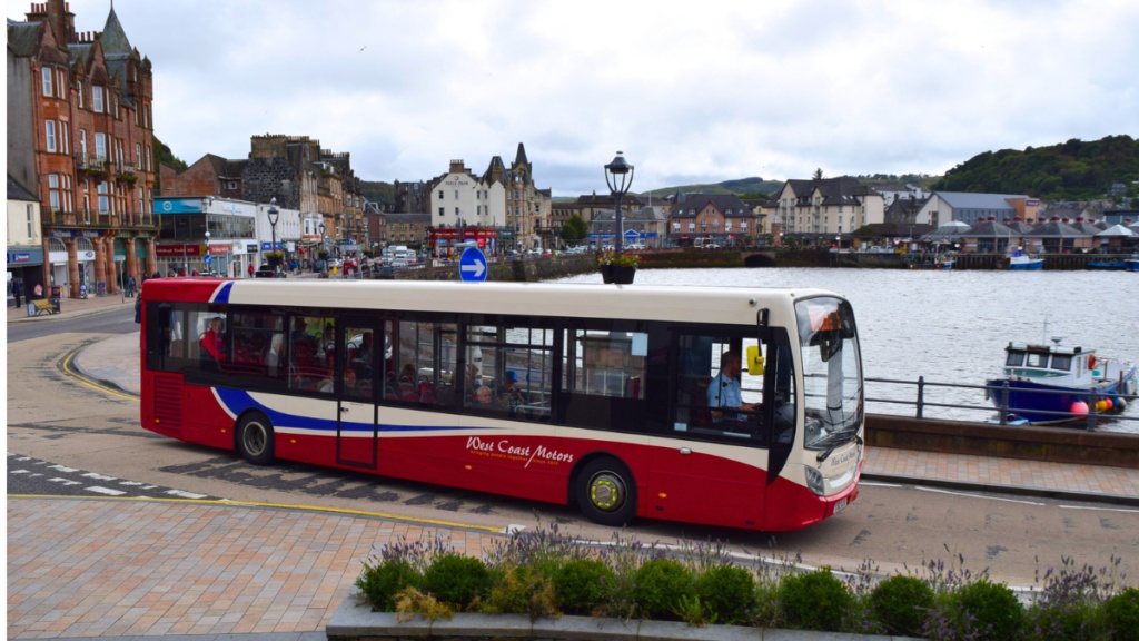 Red and cream City Sightseeing bus beside a Scottish waterfront