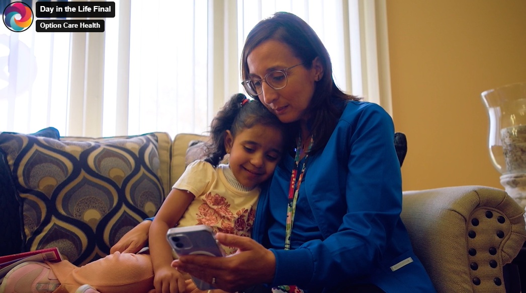 A clinician sits beside a child on a sofa in an Option Care Health company video.