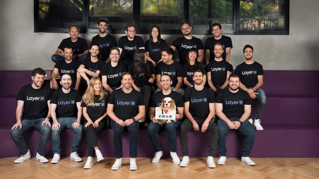 The LayerX team seated together on purple steps, with a dog in the front row