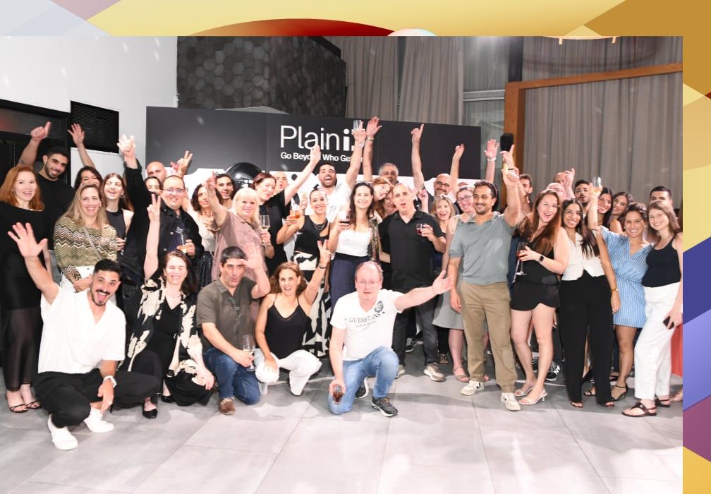 PlainID colleagues celebrating together in front of a company banner