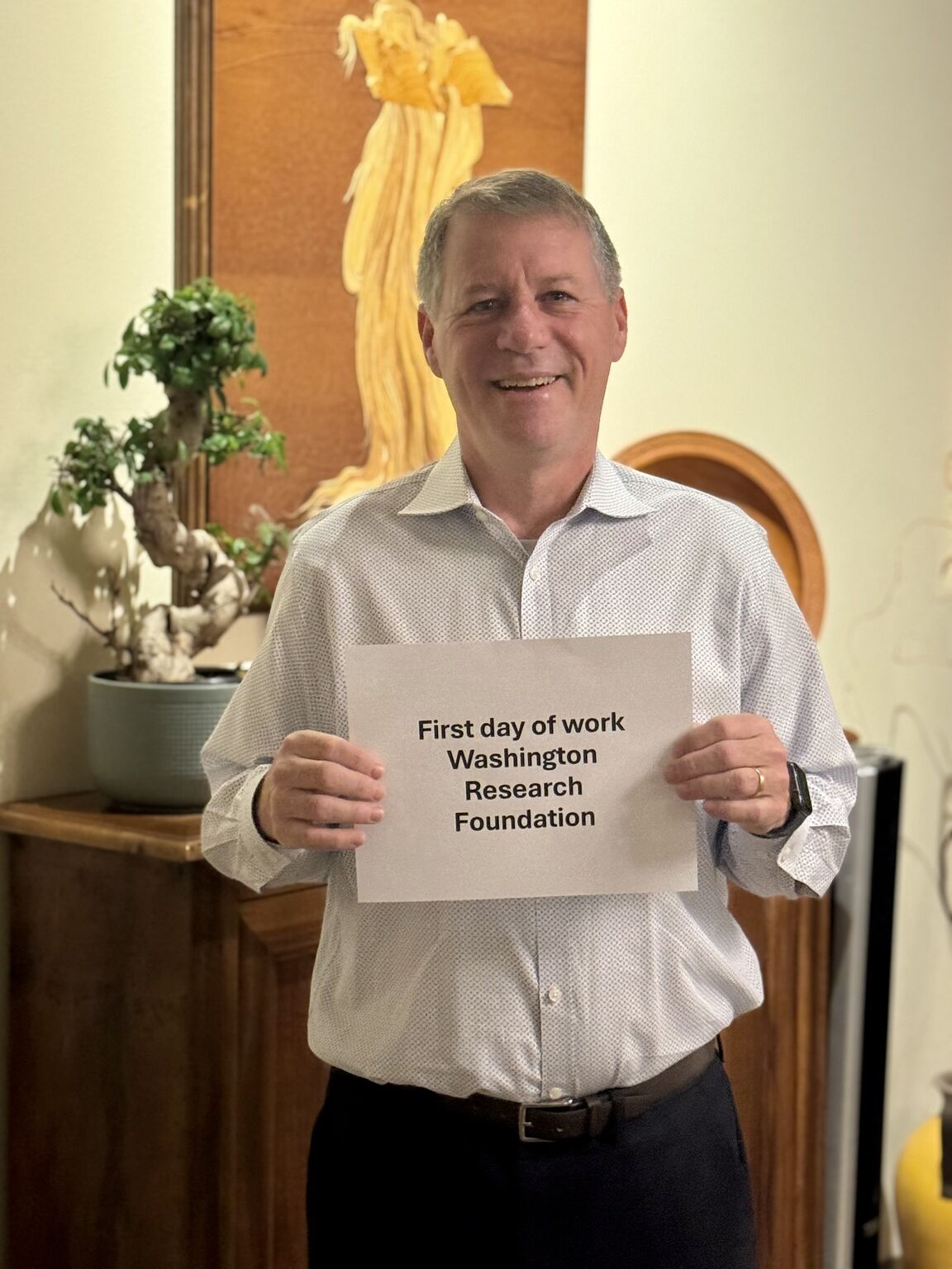Orin Levine smiling and holding a first-day-of-work sign for Washington Research Foundation