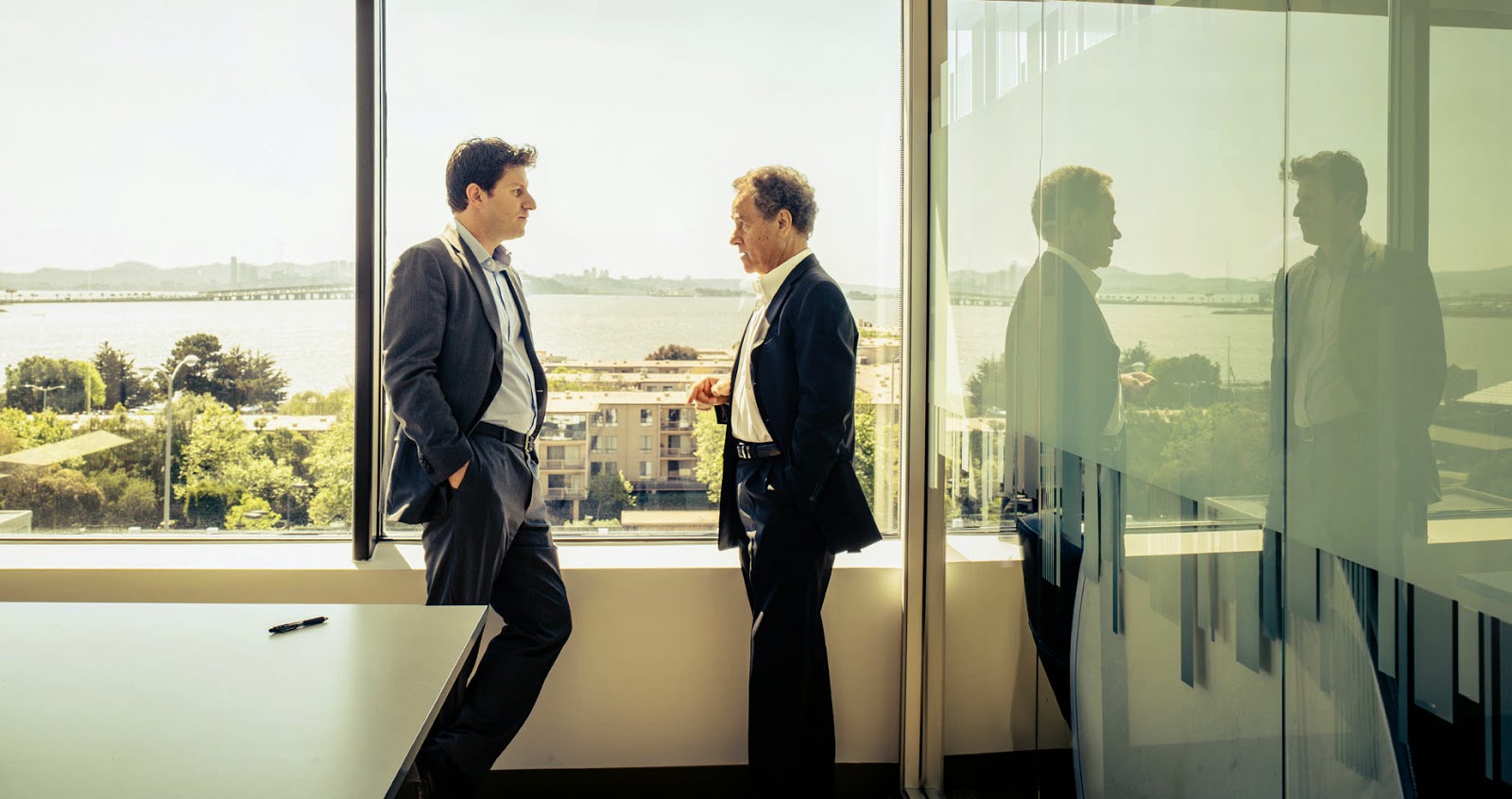 Orion Hindawi, left, in conversation with his father David beside conference-room windows