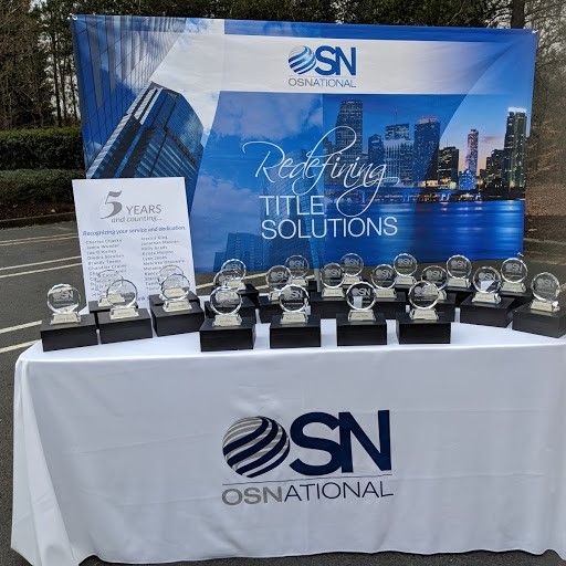 OS National anniversary awards arranged in front of a branded Redefining Title Solutions backdrop