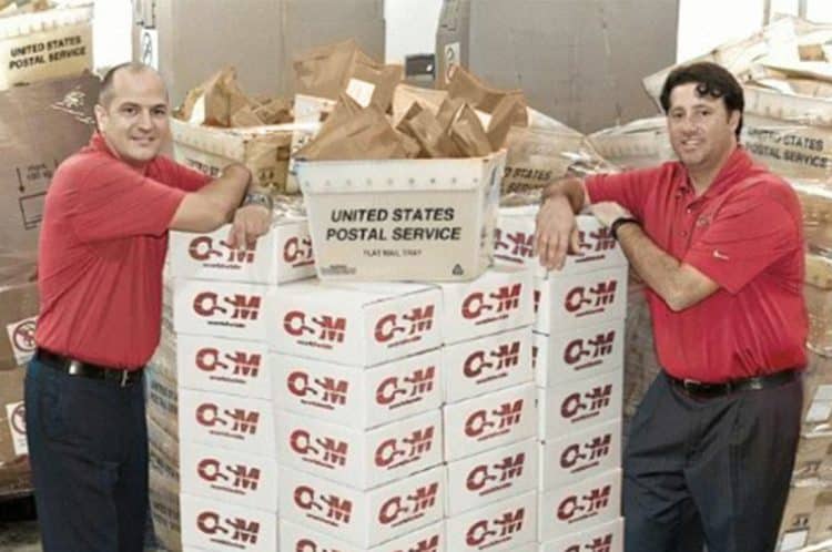 OSM co-founders beside stacks of company boxes and USPS containers