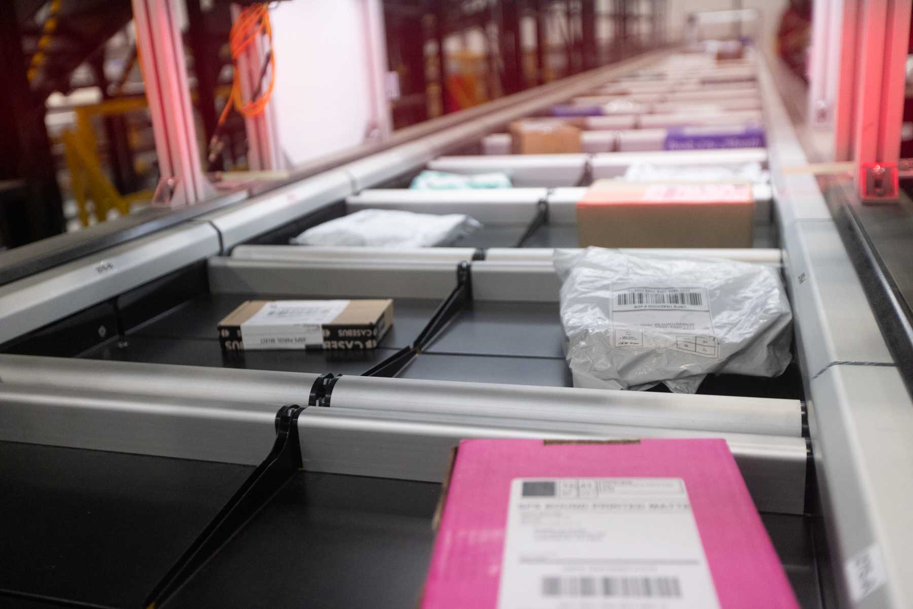 Boxes and shipping bags travel in separate trays along an OSM parcel sorting conveyor